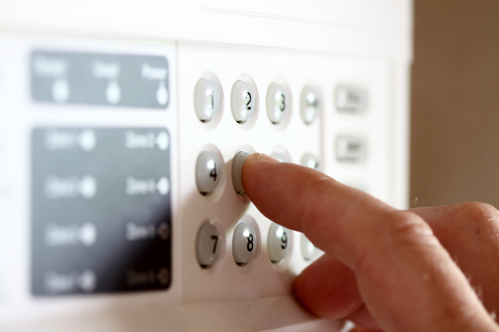 Person typing on an alarm's number pad.